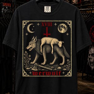 Puede incluir: Una camiseta negra de manga corta con un estampado gráfico de un lobo cargando un cordero sobre su espalda. El diseño incluye una luna creciente, una luna llena, una cruz invertida, un hacha y el texto XVIII y werwulf en rojo y crema.