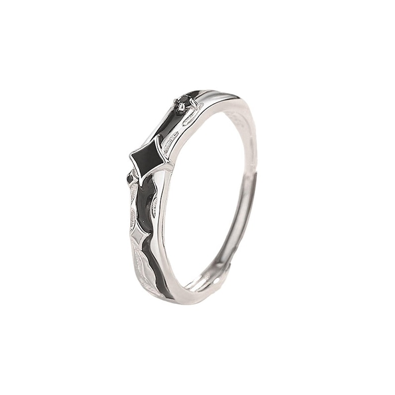 K&ouml;nnte beinhalten: Ein silberner Ring mit schwarzen Emaille-Akzenten. Der Ring hat ein geometrisches Design mit zwei schwarzen Diamantformen und einem kleinen schwarzen Stein. Das Band hat ein strukturiertes Muster und ist verstellbar.