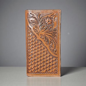 May include: A tan leather wallet with a floral and basketweave design. The wallet features a detailed embossed floral pattern on the upper right corner and a woven texture on the lower left. The edges are stitched.