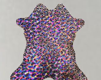 May include: A decorative rug with a unique shape and a shimmering, speckled pattern. The rug features a mix of colors, including pink, blue, yellow, and black, creating a vibrant and eye-catching design. The rug's irregular shape adds to its artistic appeal.