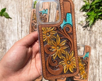 May include: A clear phone case with a brown leather back featuring a floral design with yellow flowers and turquoise accents.