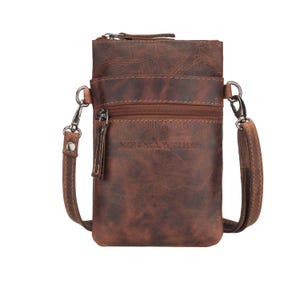 May include: A brown leather crossbody bag with a distressed finish. The bag has a zippered main compartment and a front zippered pocket. It features a detachable shoulder strap and the text "MINOLI LEATHER" is visible on the front.
