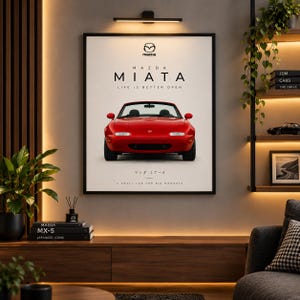 Puede incluir: Un póster de pared enmarcado que muestra un Mazda Miata descapotable rojo desde una perspectiva frontal. El texto dice Mazda Miata, Life is better open y A small car for big moments, con el logotipo de Mazda y caracteres japoneses.
