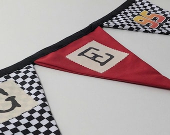 Puede incluir: Una guirnalda decorativa con banderines triangulares alternos. Algunos banderines tienen un patrón de cuadros blancos y negros, mientras que otros son de color rojo sólido. Un banderín a cuadros muestra el número 95 y otros tienen un parche beige.