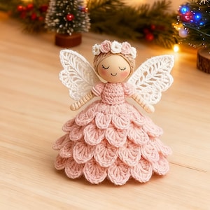 May include: A handcrafted angel figurine with a wooden head, delicate crocheted wings, and a pink crocheted dress. The angel wears a floral crown and has a serene expression. This decorative item is perfect for holiday decor.