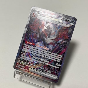 May include: A Charizard ex Pokémon trading card with a holographic design. The card features a red and black illustration of Charizard with the text "Infernal Reign" and "Burning Darkness". The card is displayed on a clear stand.