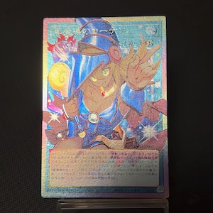 Op de afbeelding: Een holografische Yu-Gi-Oh! ruilkaart met het personage Dark Magician Girl in een blauwe outfit en hoed. De kaart bevat Japanse tekst, een geel rond icoon en een glinsterende, meerkleurige folieafwerking over het gehele oppervlak.