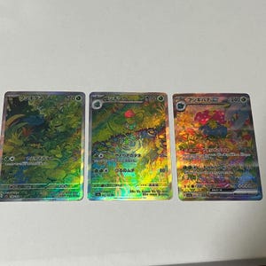 Könnte beinhalten: Drei holografische Pokémon-Sammelkarten mit den Charakteren Bisasam, Buttersaure und  Blättertanne. Die Karten sind in japanischer Sprache und zeigen die Namen der Charaktere und die Namen der Attacken.