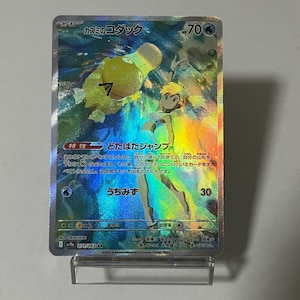 Puede incluir: Una carta coleccionable Pokémon holográfica con un Psyduck amarillo y una entrenadora. La carta tiene texto japonés y 70 PS. La carta se muestra en un soporte transparente.
