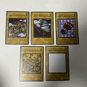 May include: Five collectible trading cards with Japanese text and illustrations. The cards feature images of a castle, a ship, a glove, and other fantasy-themed artwork. The cards have a gold border and are arranged on a white surface.