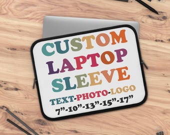 May include: A white laptop sleeve with the text "CUSTOM LAPTOP SLEEVE" in colorful letters. The text "TEXT-PHOTO-LOGO" is below the main text, with size options from 7" to 17". The sleeve is on a wooden surface.