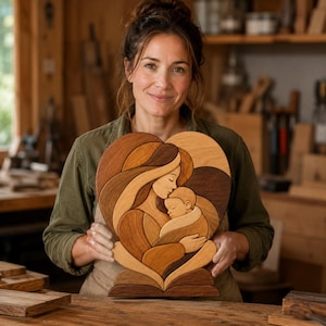 May include: A heart-shaped wooden wall art piece featuring an intricate marquetry design of a parent figure cradling a baby. The artwork is composed of various wood tones, including light, medium, and dark brown shades, forming a cohesive image.