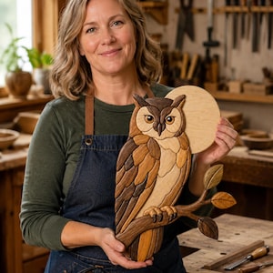 May include: A handcrafted wooden owl wall art piece featuring intricate layers of light, medium, and dark wood tones. The owl is perched on a branch with three leaves, set against a circular wooden moon background, showcasing detailed wood grain.