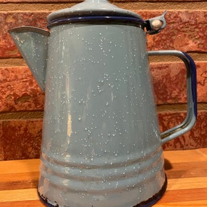 May include: A blue enamel coffee pot with a speckled finish and a blue rim. The pot has a lid with a silver knob and a handle.