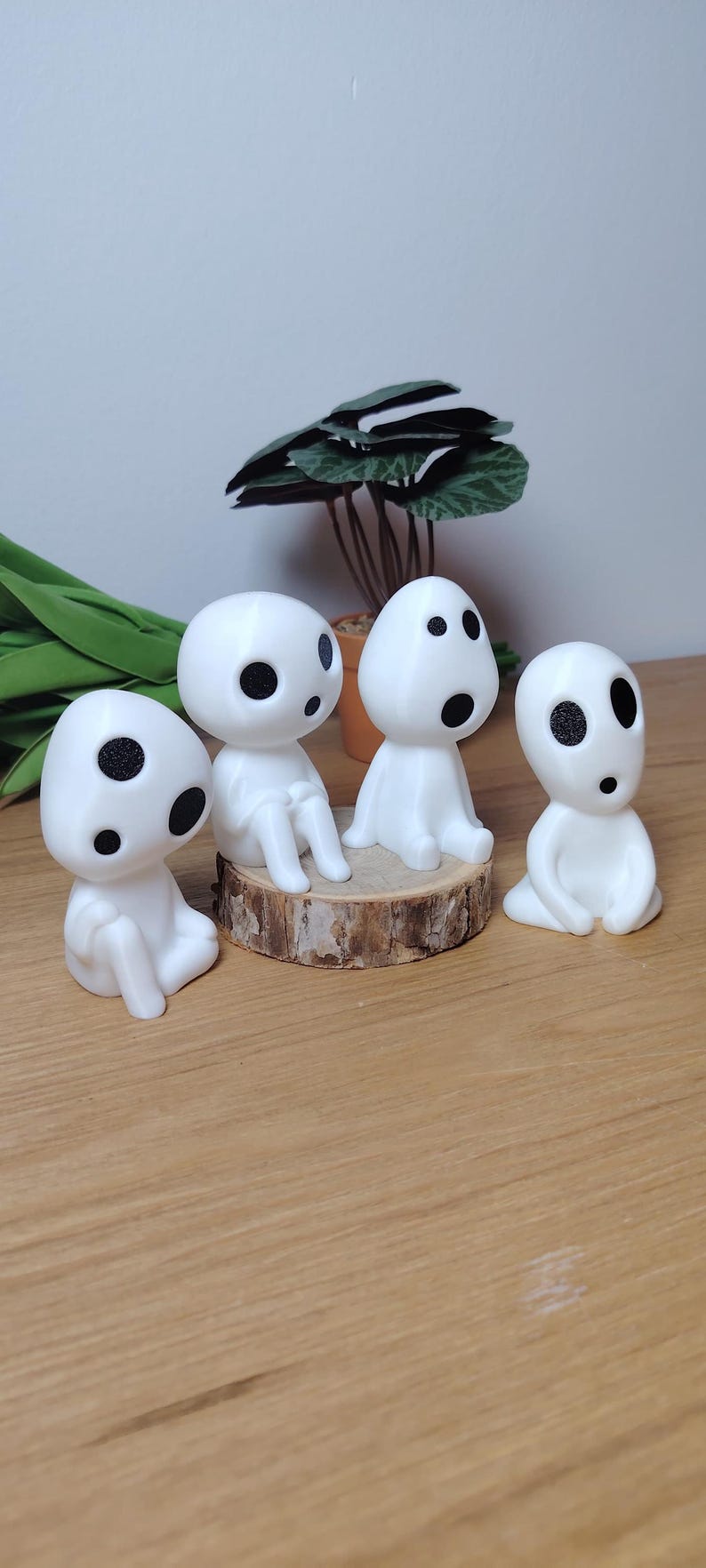K&ouml;nnte beinhalten: Vier wei&szlig;e Figuren mit schwarzen Augen, die Waldgeistern &auml;hneln, sind auf einer Holzoberfl&auml;che angeordnet. Zwei der Figuren sitzen auf einem kleinen Holzscheit, w&auml;hrend die anderen beiden auf der Oberfl&auml;che sitzen.