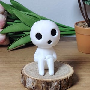 K&ouml;nnte beinhalten: Wei&szlig;e 3D-gedruckte Figur eines Charakters aus dem Film "Mein Nachbar Totoro". Die Figur sitzt auf einer Holzscheibe.