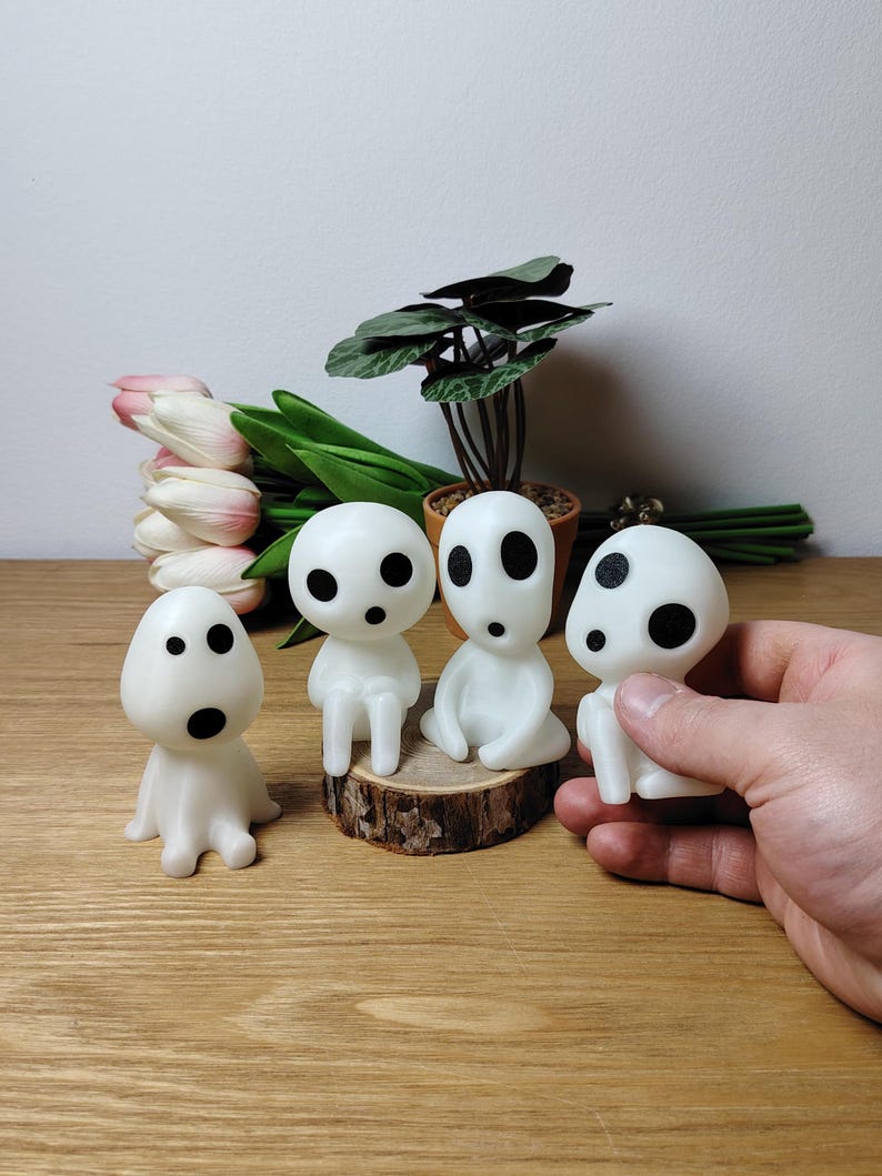 May include: Four white, glowing, spirit-like figures with black eyes. Three of the figures are sitting on a wooden log, while the fourth figure is being held in a hand.