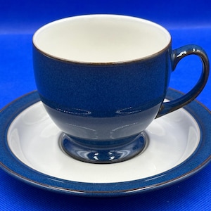 May include: A blue and white teacup and saucer set. The teacup has a dark blue exterior with a white interior and a brown rim. The saucer is white with a blue border. Ideal for serving tea or coffee.
