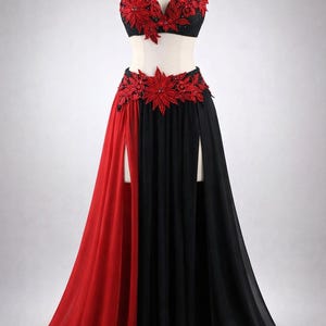 May include: A black and red belly dance costume on a mannequin. The costume features a black bra and skirt with red floral embellishments. The skirt has a split design, with a red panel on one side and a black panel on the other.