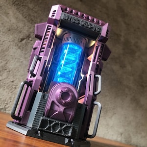 Könnte beinhalten: Ein futuristisches, lila Gerät mit dem Text "MYGS-055-YC" oben. Das Gerät hat einen leuchtend blauen Kern und eine schwarze Basis. Das Design weist komplizierte Details und eine mechanische Ästhetik auf.