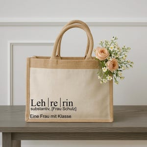 Könnte beinhalten: Eine beigefarbene Tragetasche mit einem Canvas-Einsatz. Die Tasche hat einen Jute-Ober- und Unterteil und trägt den Text "Leh|re|rin substantiv, [Frau Schulz] Eine Frau mit Klasse." in Schwarz.