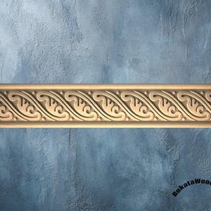 May include: A light-coloured wooden moulding strip featuring a continuous carved pattern of repeating wave-like scrolls and small circular beads. The decorative trim is positioned horizontally across the frame. The text BukataWoodwork is visible.