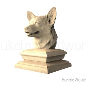 May include: A carved wooden sculpture of a dog's head, mounted on a tiered base. The dog's head is detailed with open mouth and upright ears. The sculpture is light brown and has the text "Bukata Woodwork".
