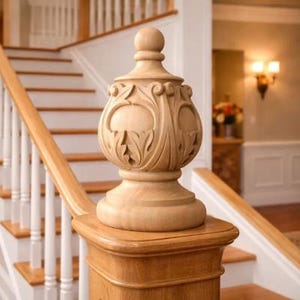 May include: A decorative wooden newel post finial with intricate carved floral designs. The finial is light brown and sits atop a wooden newel post on a staircase with white balusters and wooden steps. The overall style is classic and elegant.