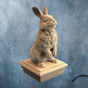 May include: A detailed wooden sculpture of a rabbit, seated upright on a layered wooden base. The rabbit has long ears and a textured fur appearance. The sculpture is set against a textured blue background. The artist's name, "BukatWoodwork", is visible.