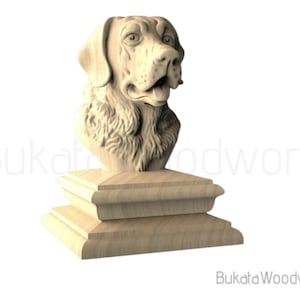 May include: A wooden sculpture of a dog's head, mounted on a tiered base. The dog has detailed fur and facial features. The sculpture is made of light-colored wood and is set against a white background. The text "Bukata Woodwork" is visible.