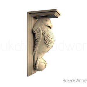 May include: A carved wooden corbel featuring an eagle design. The eagle is depicted with detailed feathers, a sharp beak, and a ball held in its talons. The corbel is a light brown color and has the text "Bukata Woodwork".