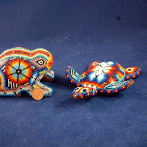 May include: Two small, colorful, beaded animal figurines. A frog and a turtle, both with intricate patterns in shades of blue, red, yellow, and white.
