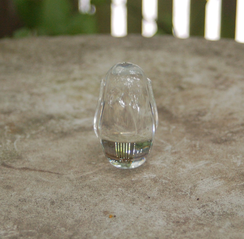 May include: A clear glass bottle stopper with a rounded shape and a textured surface.