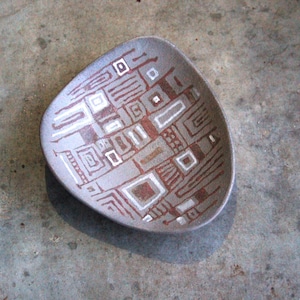 Könnte beinhalten: Eine graue Keramikschale mit einem geometrischen Muster in Weiß und Braun. Das Muster zeigt Quadrate, Linien und andere abstrakte Formen.