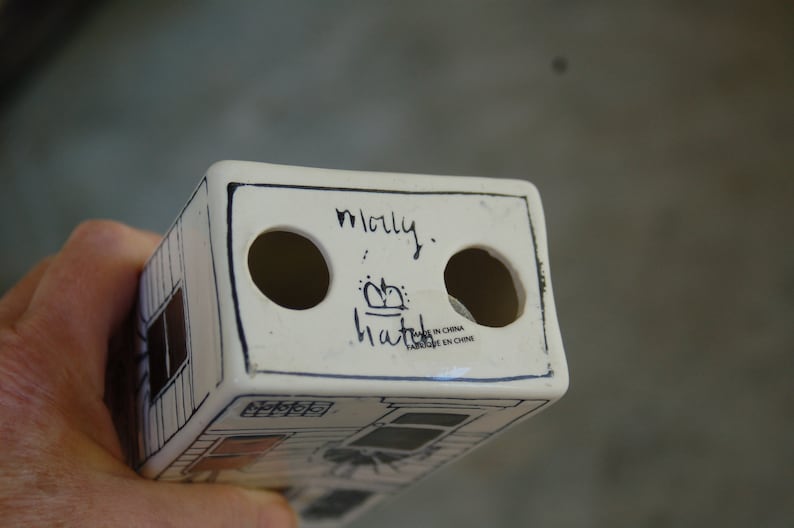 May include: White ceramic toothbrush holder with two holes and black writing that says "molly.  hattie" and "Made in China Fabrique en Chine".