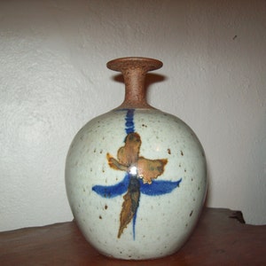 May include: A white ceramic vase with a brown rim and a blue and brown abstract design.
