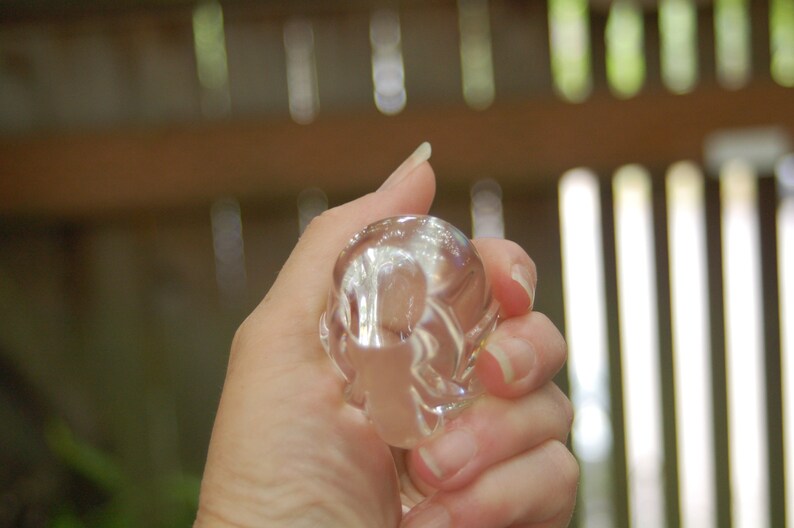 May include: A clear glass paperweight with a swirling, abstract design. The paperweight is being held in a hand.