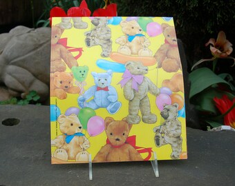 Puede incluir: Papel de regalo amarillo con un patrón de osos de peluche sosteniendo globos. Los osos son marrones, azules y blancos. Algunos de los globos son rojos, azules y verdes.