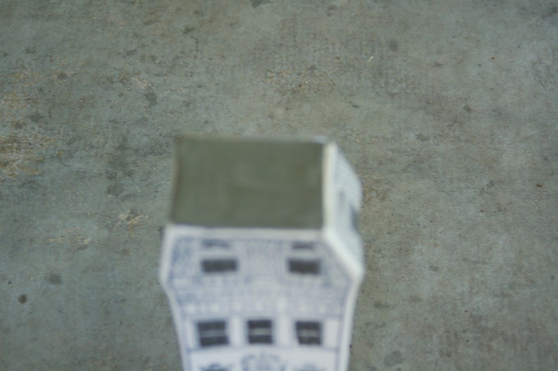 May include: A white ceramic house with a gray roof. The house has multiple windows and a detailed design.