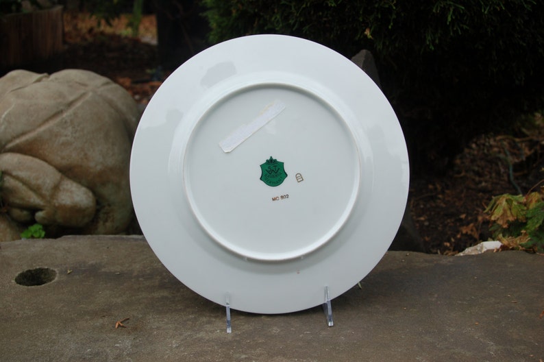 Peut inclure: Assiette en c&eacute;ramique blanche avec un logo vert et or au dos. Le logo repr&eacute;sente un bouclier avec une couronne et le texte "Made in Italy".