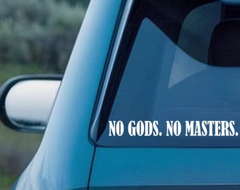 Pode incluir: Autocolante de vinil branco com o texto "NO GODS. NO MASTERS." aplicado no vidro traseiro de um carro turquesa. O autocolante está centrado e numa fonte sem serifa. O espelho retrovisor lateral do carro é visível.