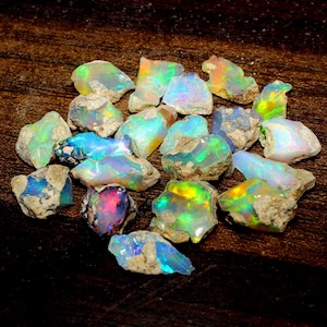 Peut inclure: Une collection de pierres précieuses d'opale brute dans différentes nuances de bleu, vert et jaune. Les opales sont irisées et ont un aspect naturel et brut.