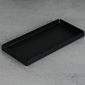 Könnte beinhalten: Ein schwarzes rechteckiges Tablett mit leicht abgerundeten Kanten. Das Tablett ist aus Metall und hat eine matte Oberfläche.
