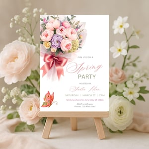 Op de afbeelding: Een witte uitnodigingskaart op een houten ezel, met een bloemenboeket met roze en paarse bloemen, een roze lint en de woorden "Spring Party". Een vlindergrafiek staat linksonder.