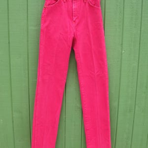 Peut inclure: Un pantalon en jean rose vif suspendu &agrave; un cintre en m&eacute;tal. Le jean a une conception classique &agrave; cinq poches avec une fermeture &agrave; bouton et &agrave; glissi&egrave;re. Le pantalon est en denim robuste et est d'une teinte rose vibrante.
