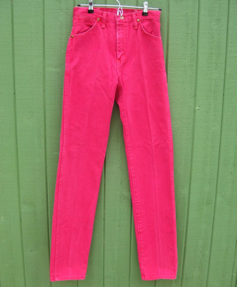 Peut inclure: Un pantalon en jean rose vif suspendu &agrave; un cintre en m&eacute;tal. Le jean a une conception classique &agrave; cinq poches avec une fermeture &agrave; bouton et &agrave; glissi&egrave;re. Le pantalon est en denim robuste et est d'une teinte rose vibrante.
