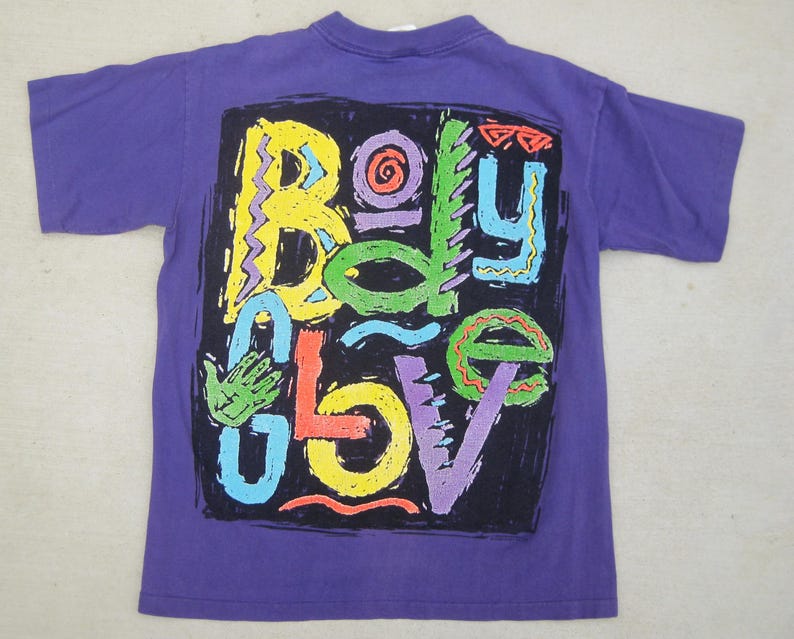 May include: A purple t-shirt with a colorful graphic design. The design features the words "Body Glove" in a variety of bright colors, including yellow, green, orange, and blue, set against a black background.