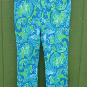 May include: A pair of vintage, high-waisted pants with a vibrant, swirling pattern in shades of blue and green. The fabric has a slight sheen, and the pants are hanging on a hanger. A retro, eye-catching garment.