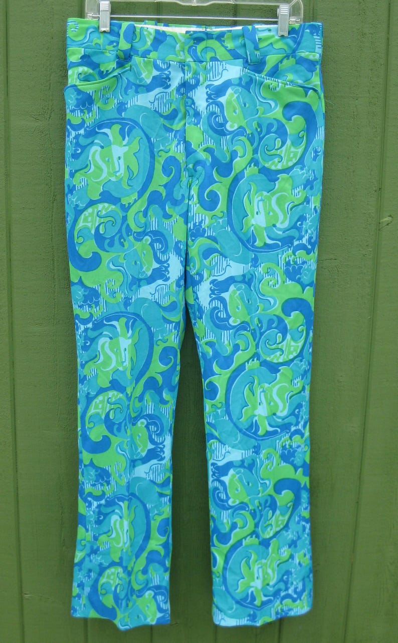 May include: A pair of vintage, high-waisted pants with a vibrant, swirling pattern in shades of blue and green. The fabric has a slight sheen, and the pants are hanging on a hanger. A retro, eye-catching garment.
