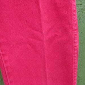 Peut inclure: Gros plan sur une section d'un pantalon en jean rose vif. Le tissu pr&eacute;sente une texture subtile et des coutures le long de la couture lat&eacute;rale. Le pantalon est d'une couleur unie et vibrante, sugg&eacute;rant un style d&eacute;contract&eacute;.